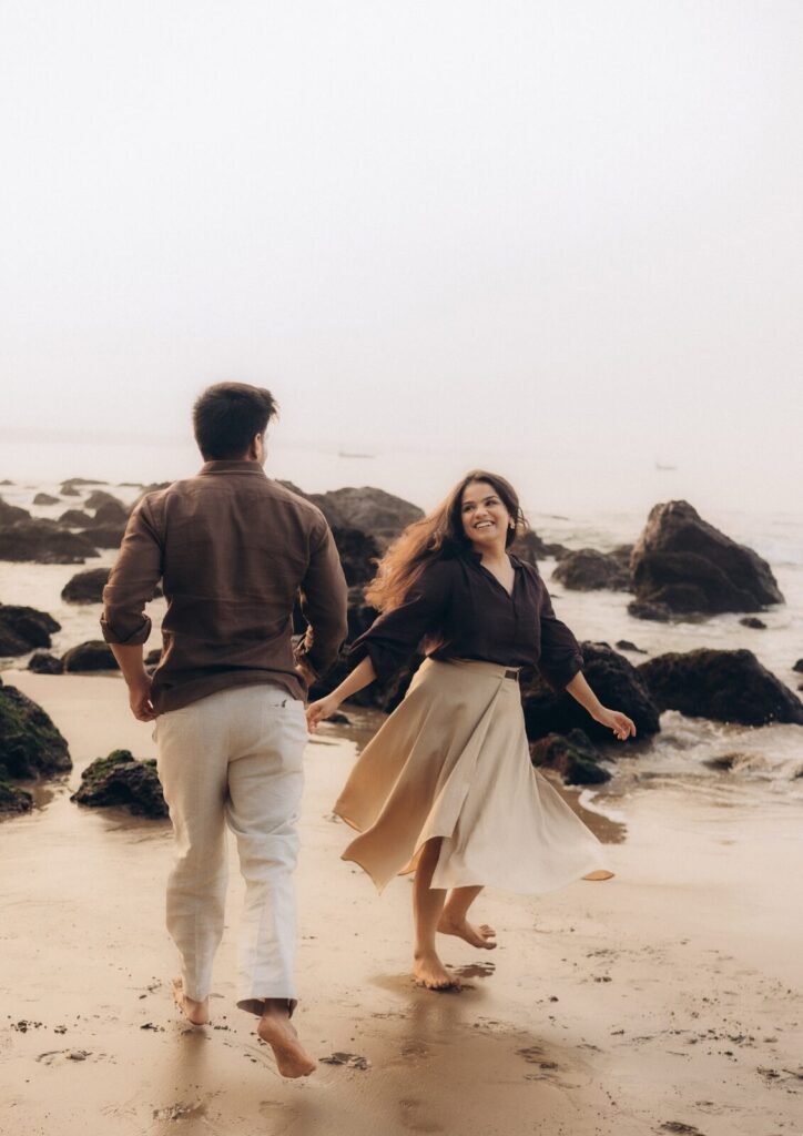 Couple running barefoot on a Goa beach during their pre-wedding shoot by Pavan Soni
